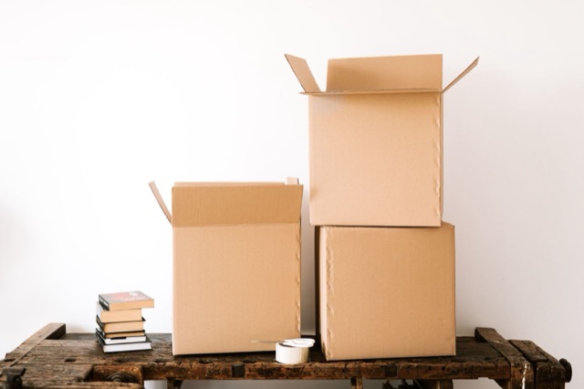 Open cardboard boxes and stacked books on a wooden table