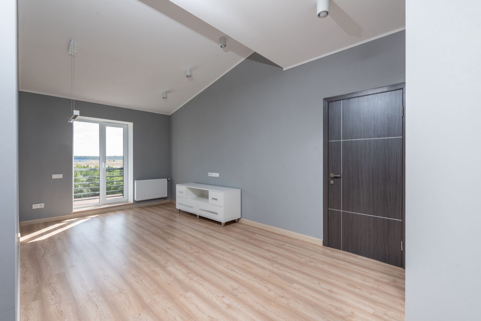 Empty modern living room with wood-look floor and balcony door