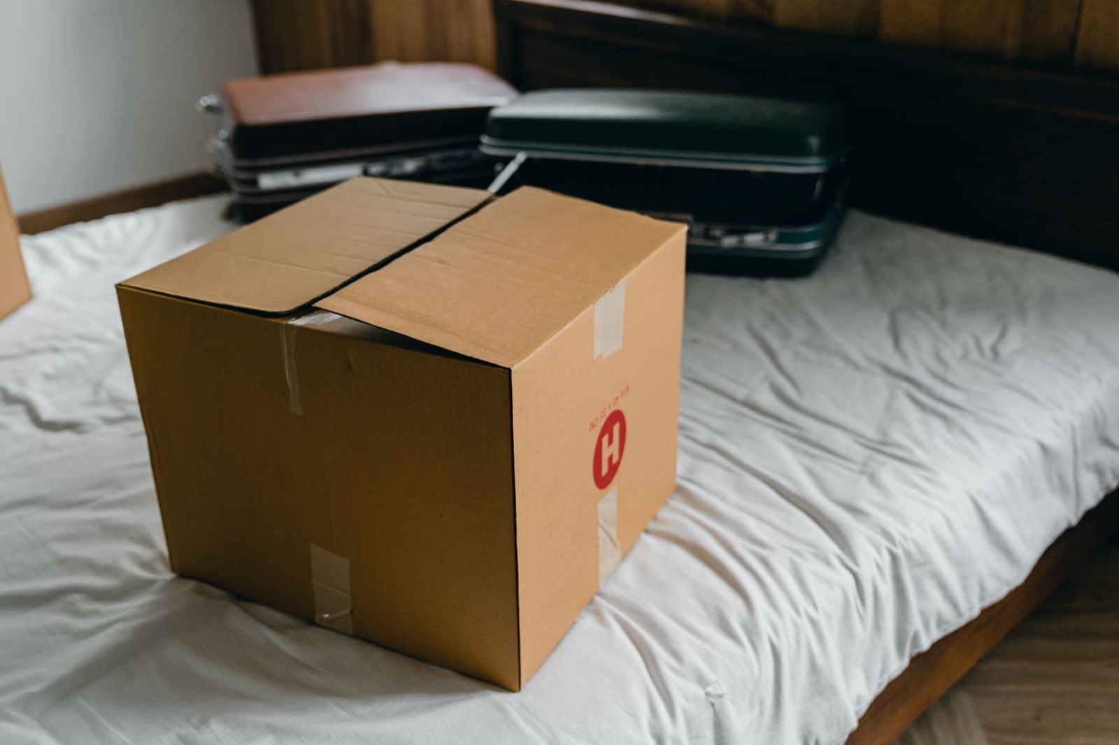 Moving box and suitcases packed on a bed