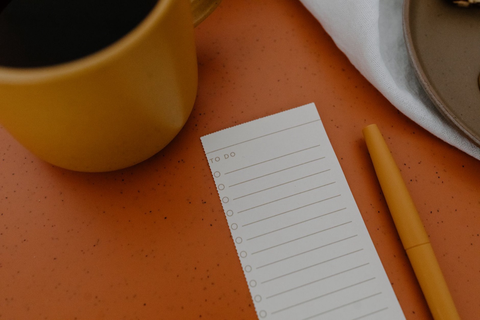 To-do list, pen and coffee mug on a table