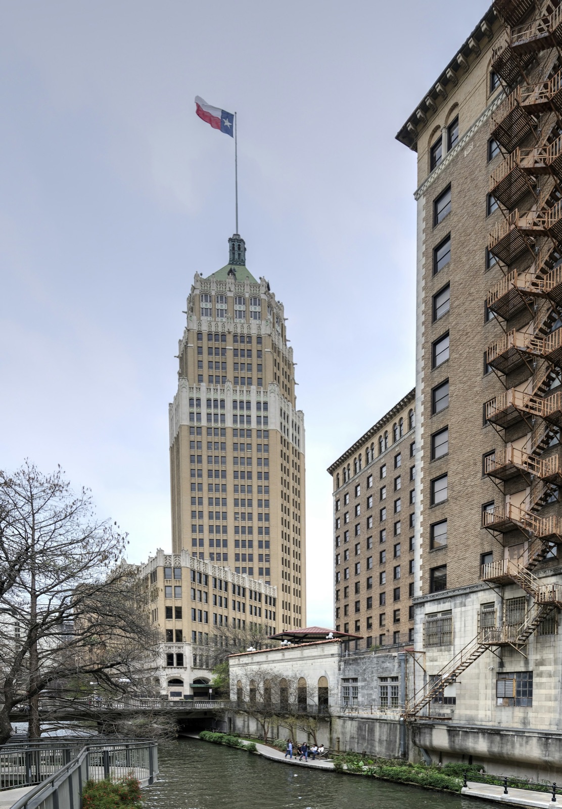 The Tower Life Building flying the Texas flag over the San Antonio River